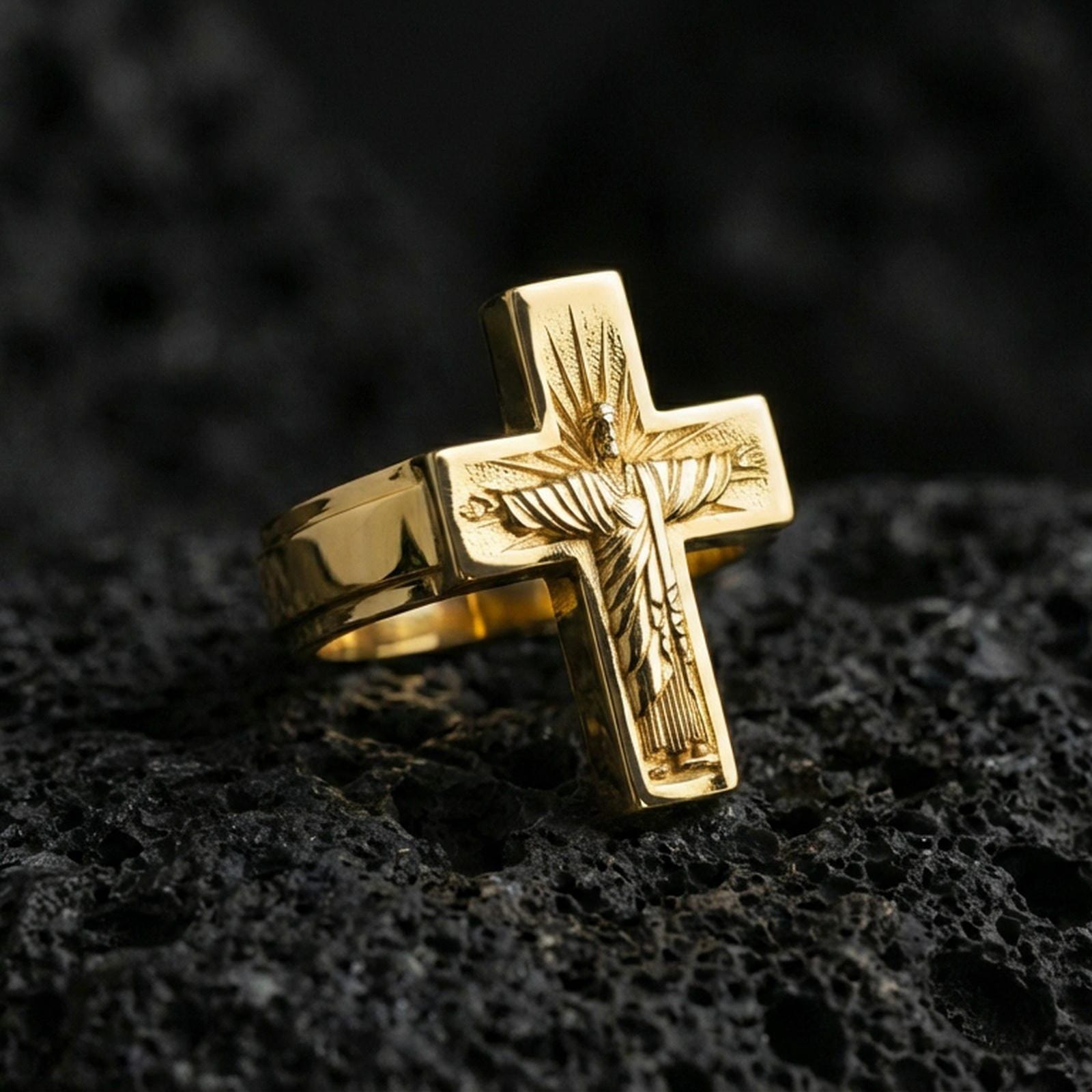 Gold plated Jesus crucifix ring on dark volcanic rock, Christian cross statement ring, engraved Christ figure and sunburst halo