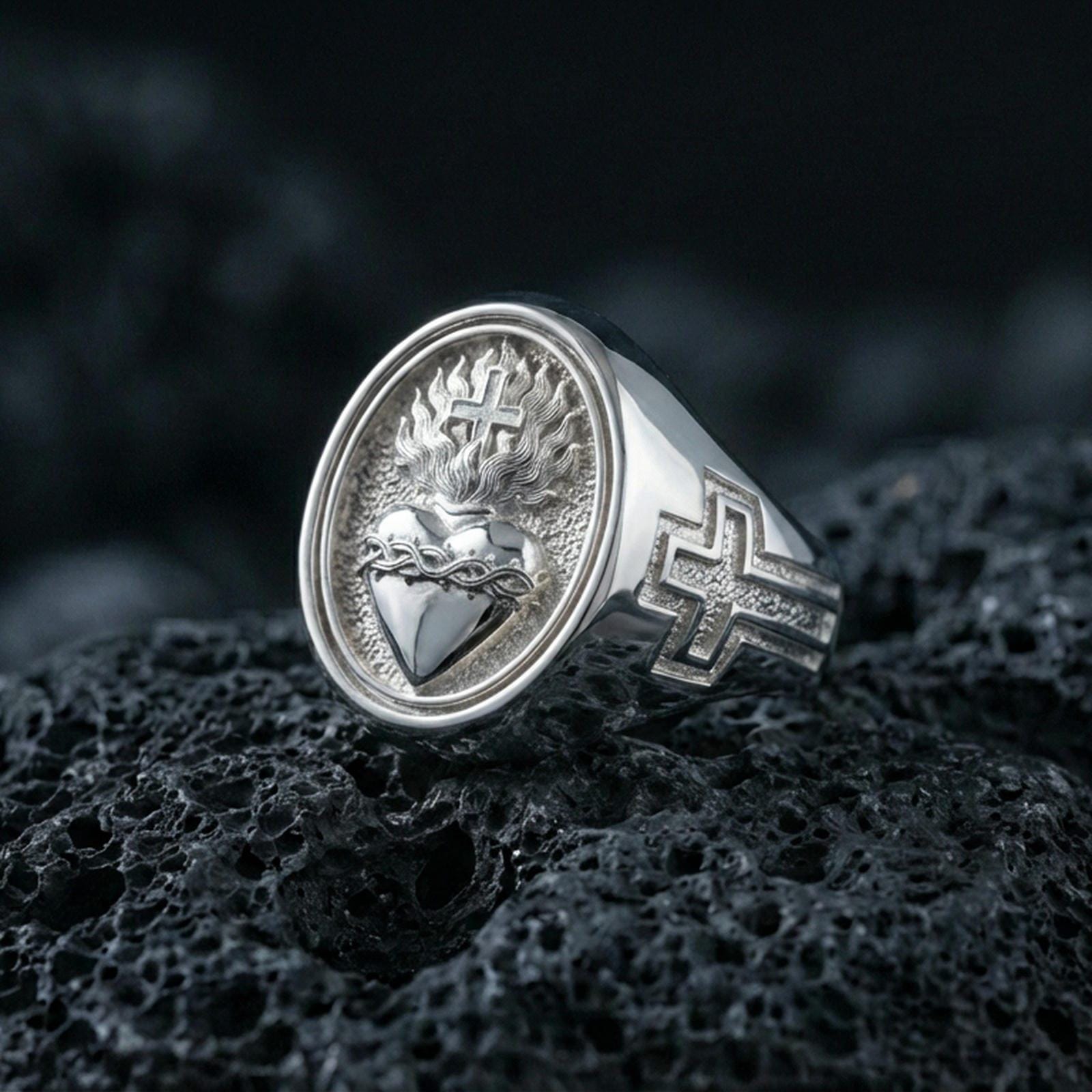 Polished silver Sacred Heart signet ring on porous volcanic stone, engraved flaming heart with crown of thorns, bold faith symbol ring