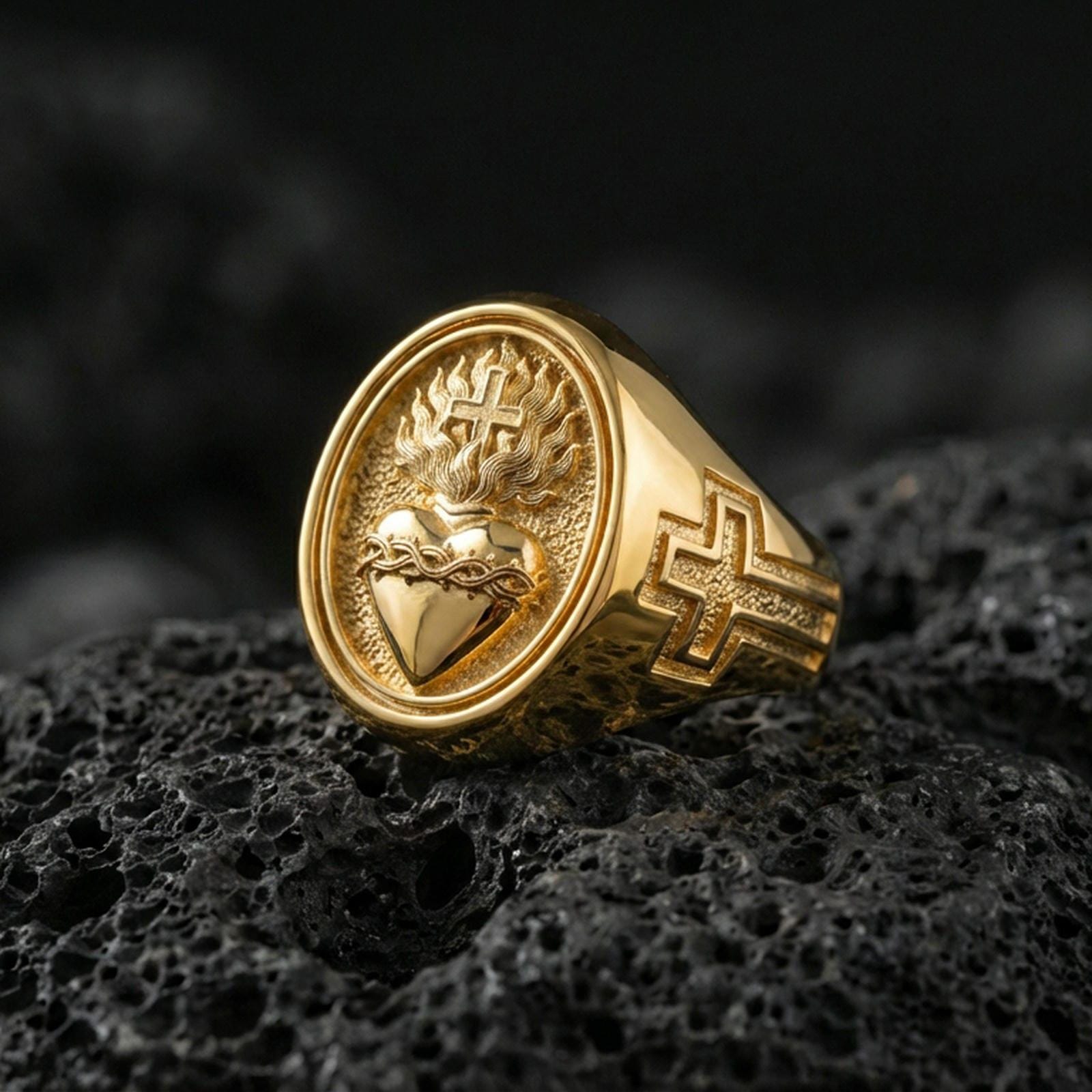 Gold plated Sacred Heart signet ring on dark volcanic rock, flaming heart and cross motif, Catholic devotional statement ring