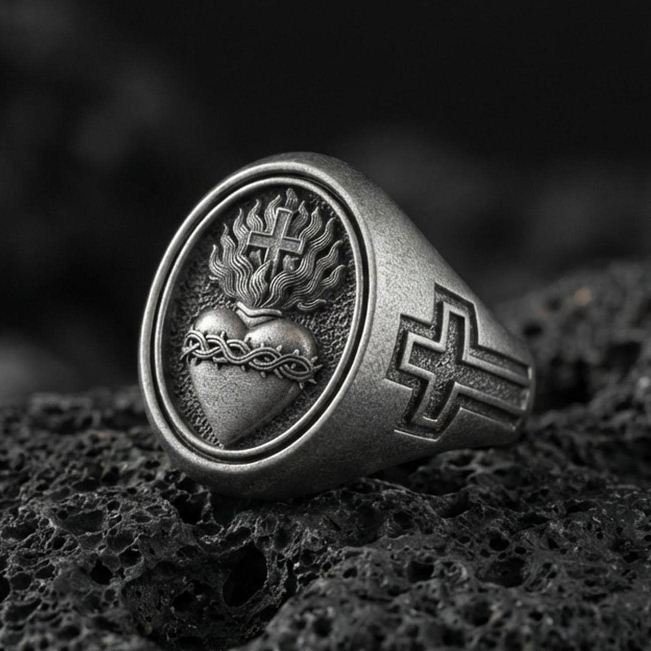 Oxidized 925 sterling silver Sacred Heart signet ring on volcanic rock, flaming heart and cross emblem, Christian devotion jewelry