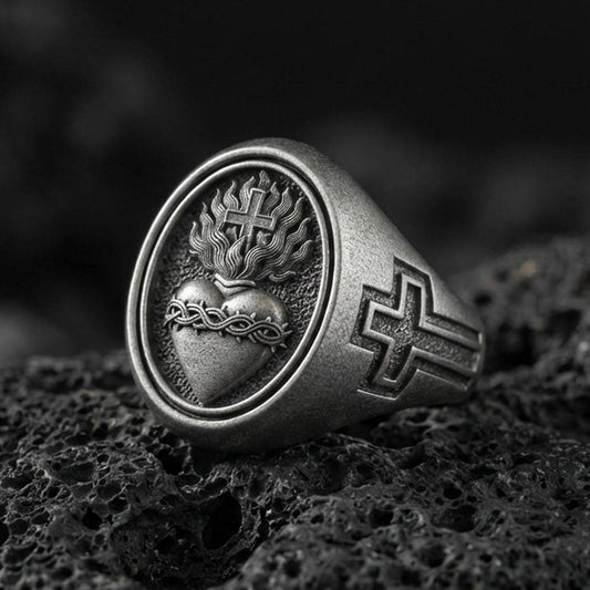 Oxidized 925 sterling silver Sacred Heart signet ring on volcanic rock, flaming heart and cross emblem, Christian devotion jewelry