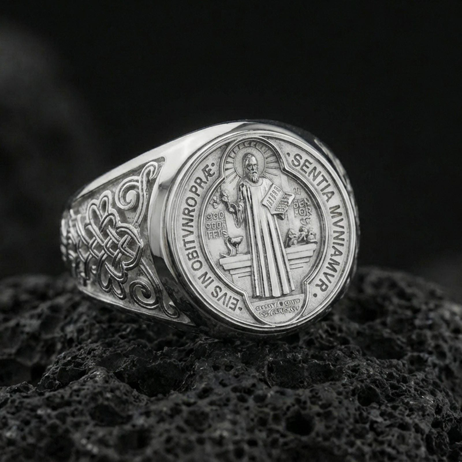Polished silver St Benedict medal signet ring on porous volcanic stone, engraved saint figure and inscription, Christian faith jewelry