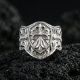 Load image into Gallery viewer, Polished silver heraldic cross shield signet ring on porous volcanic stone, raised shield crest and detailed scrollwork band
