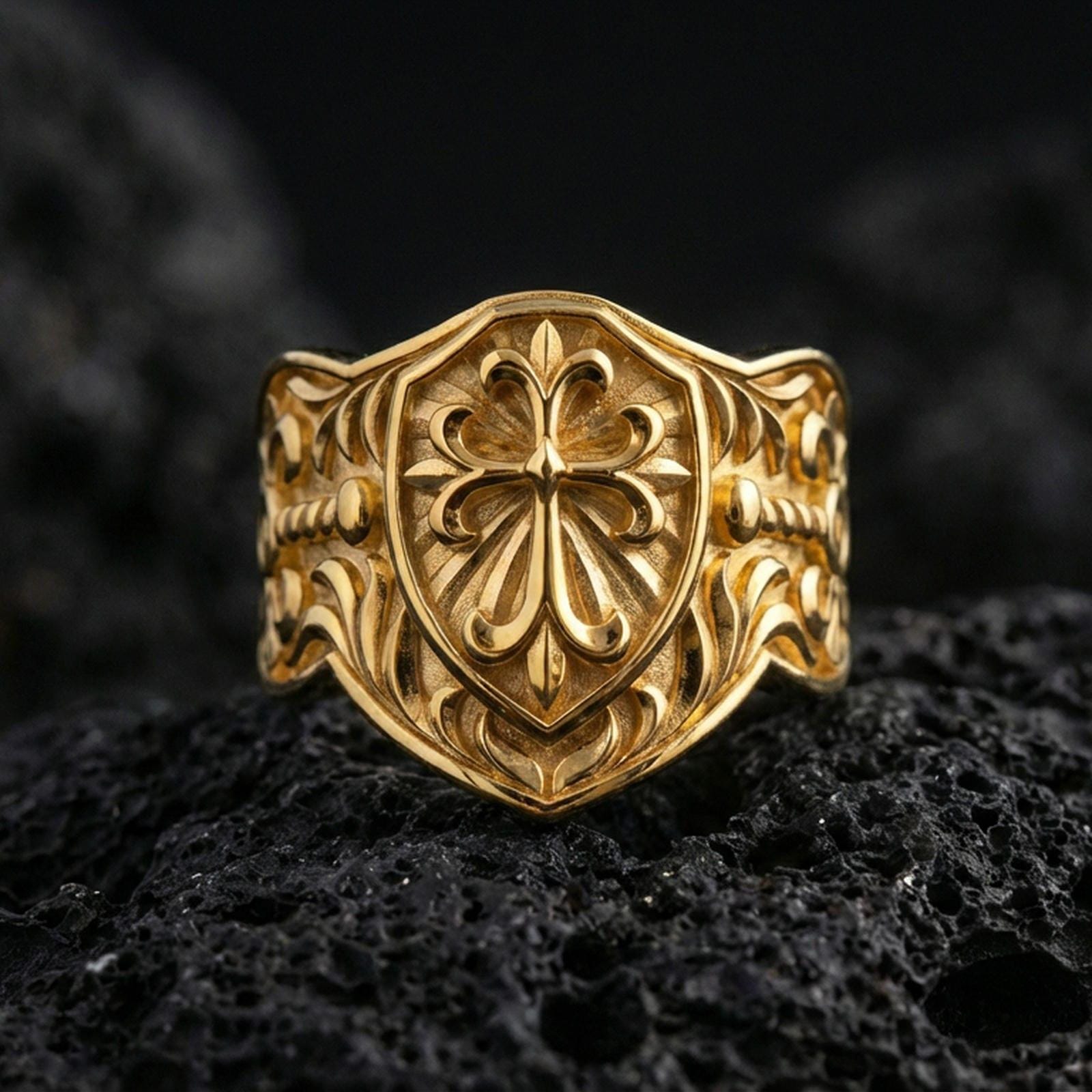 Gold plated heraldic cross shield ring on dark volcanic rock, medieval crest design with ornate cross and engraved band