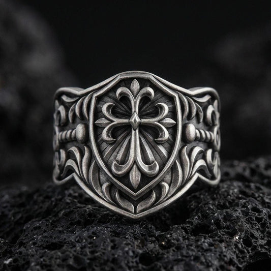 Oxidized 925 sterling silver heraldic cross shield ring on volcanic rock, ornate fleur-de-lis style cross and baroque engravings