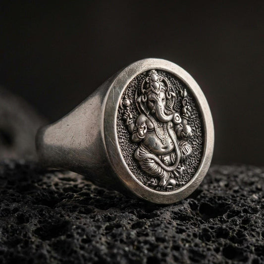 Oxidized 925 sterling silver Ganesha signet ring on volcanic rock, detailed elephant deity relief and textured background