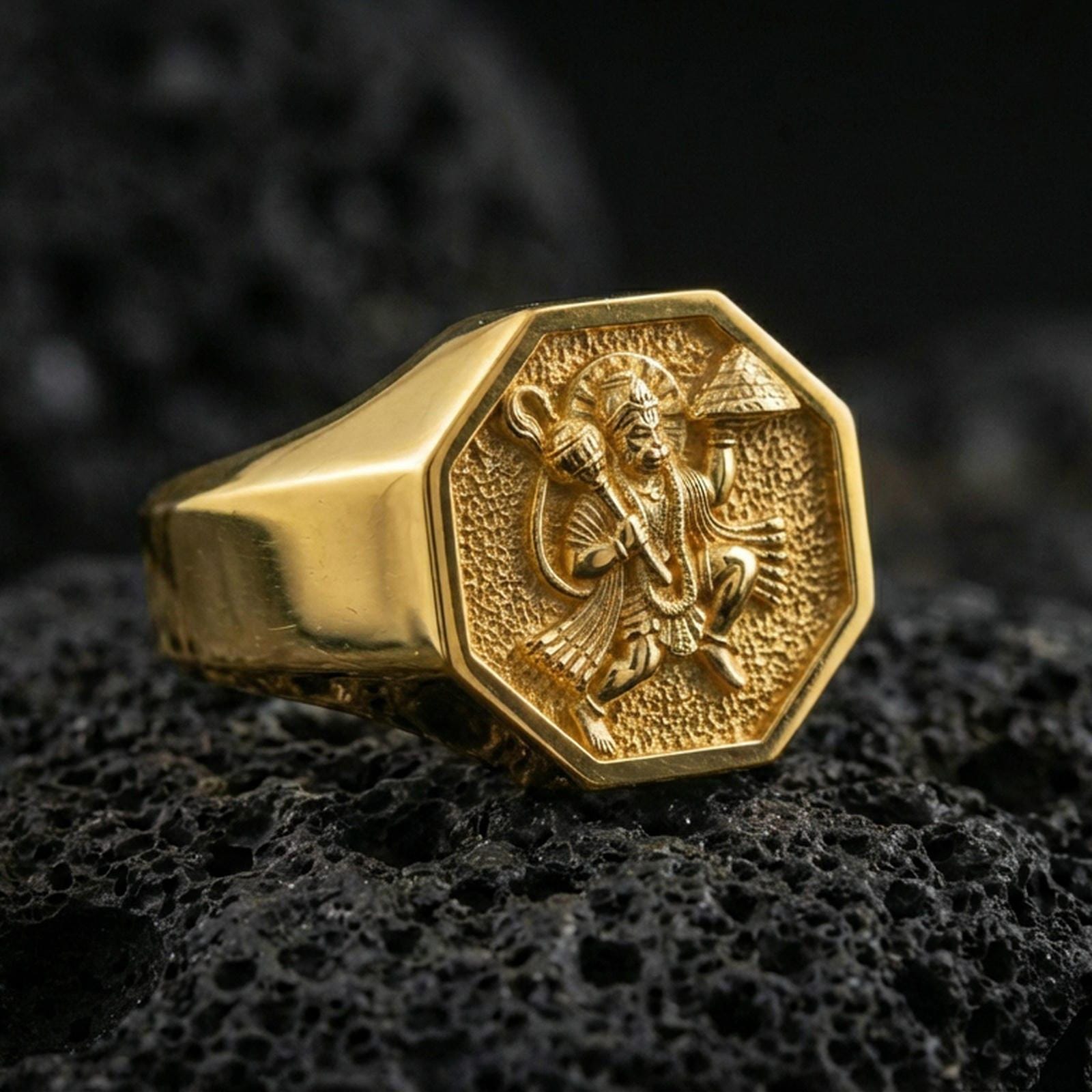Gold plated Hanuman signet ring on dark volcanic rock, Hindu monkey god relief ring with bold octagon face and sharp edges