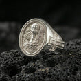 Load image into Gallery viewer, Polished silver Eucharist signet ring on porous volcanic stone, oval face with chalice, host, and ornate Christian scrollwork
