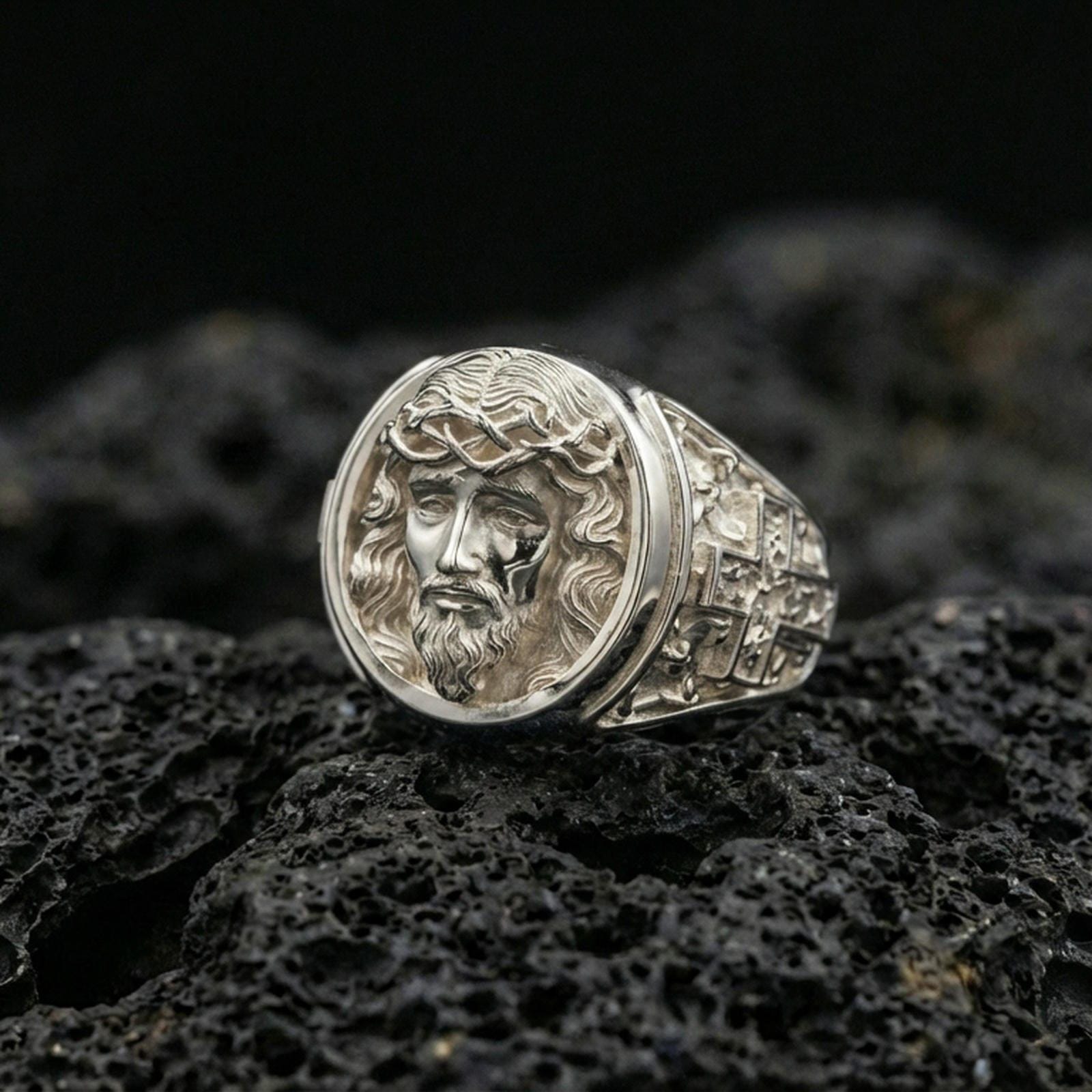Polished silver Jesus Christ ring on porous volcanic stone, detailed face relief with clean shine and smooth round bezel