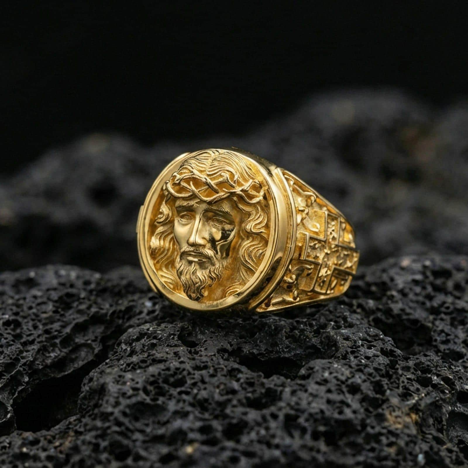 Gold plated Jesus ring on dark volcanic rock, crown of thorns portrait signet with warm tone and crisp sculpted depth