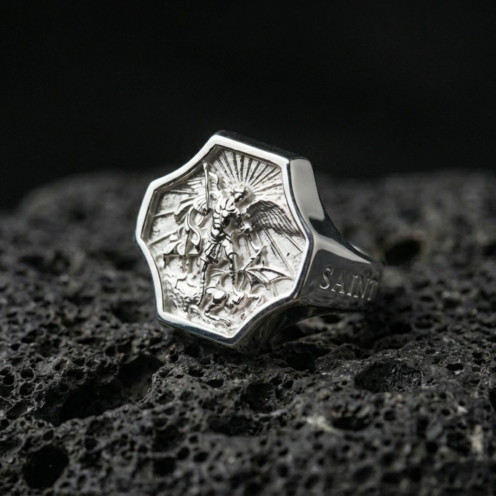 Polished silver Saint Michael signet ring on porous volcanic stone, crisp octagonal bezel and detailed guardian relief