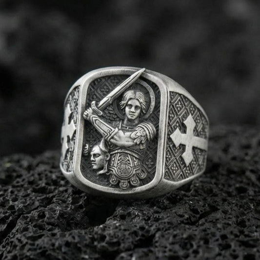 Oxidized Finish silver Saint Michael signet ring on porous volcanic stone, archangel with sword engraving, cross side detail close-up