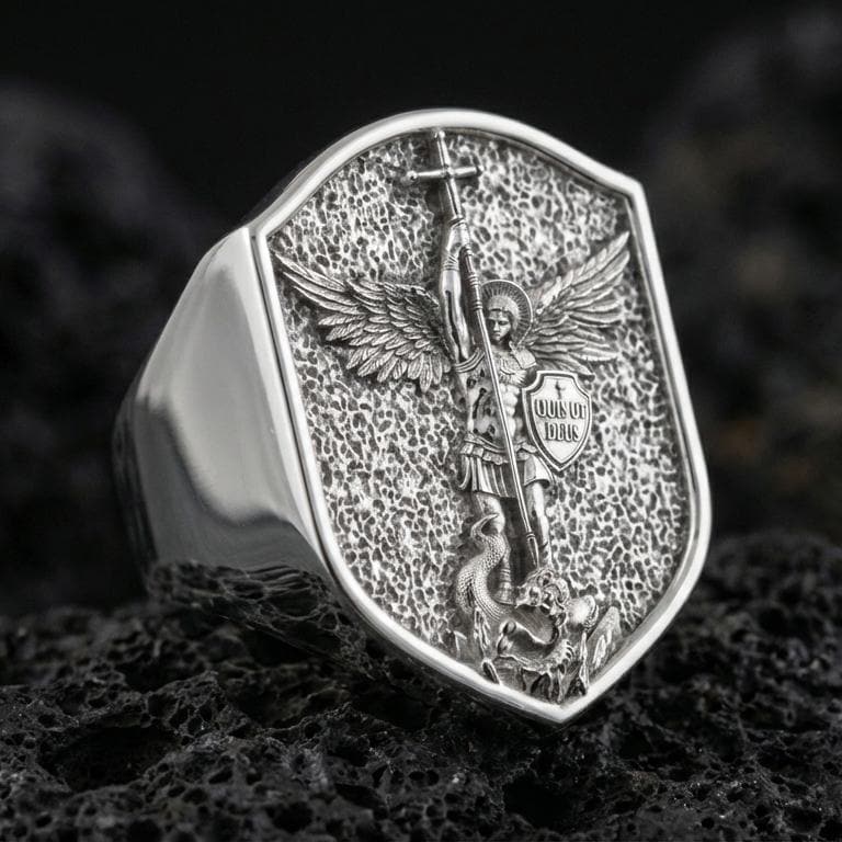 Polished silver Saint Michael signet ring on porous volcanic stone, “Quis ut Deus” shield detail and hammer-texture face