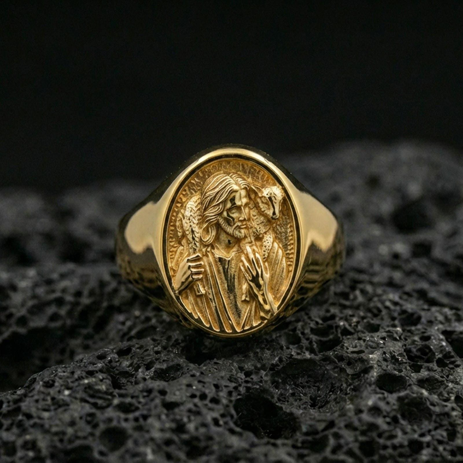 Gold plated Jesus the Good Shepherd signet ring on dark volcanic rock, detailed shepherd and lamb relief medallion face