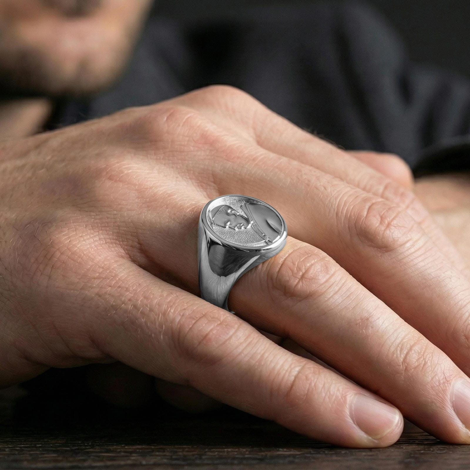 Polished silver Pope portrait ring worn on finger, papal profile relief with smooth bezel signet