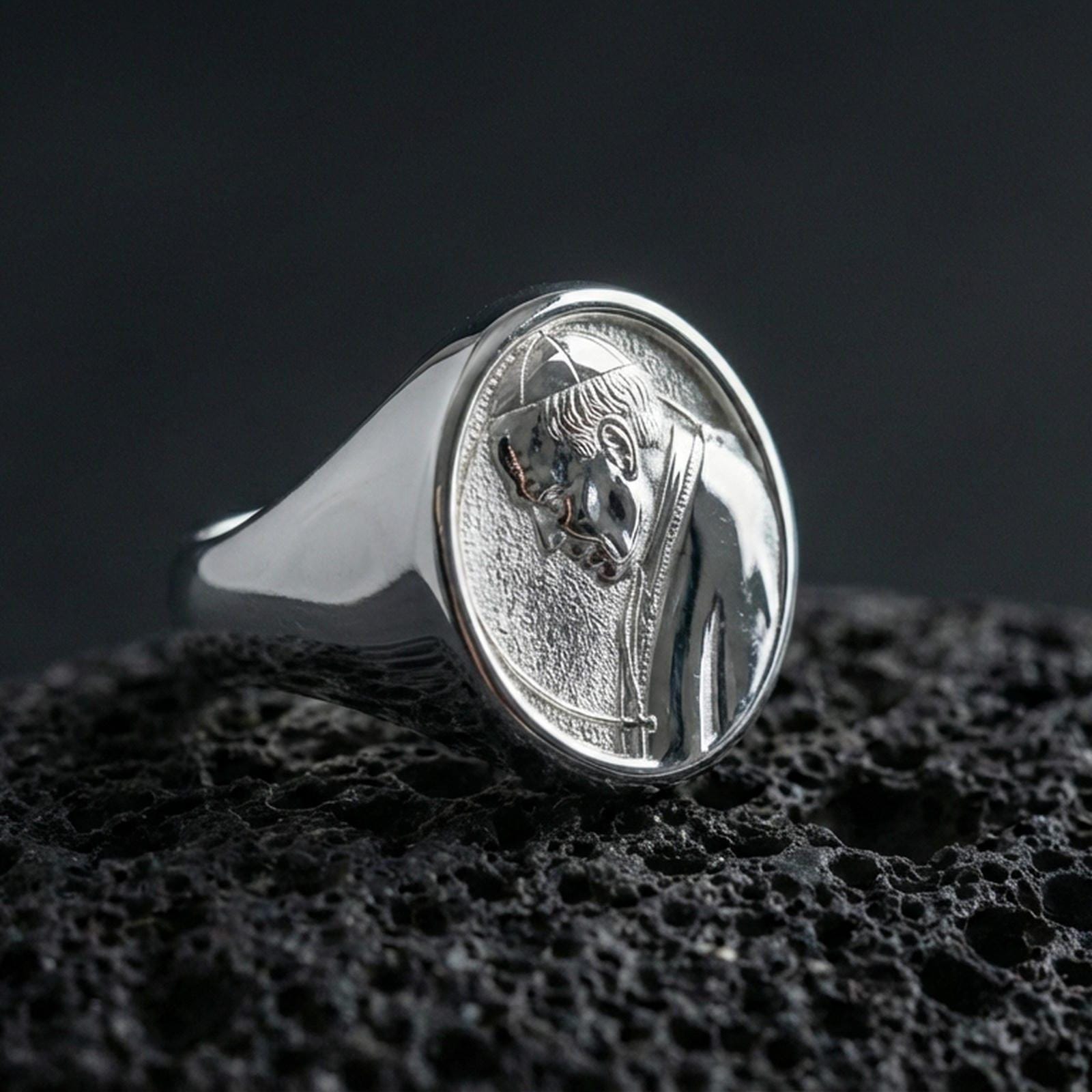 Polished silver Pope portrait ring on porous volcanic stone, detailed papal profile relief signet design