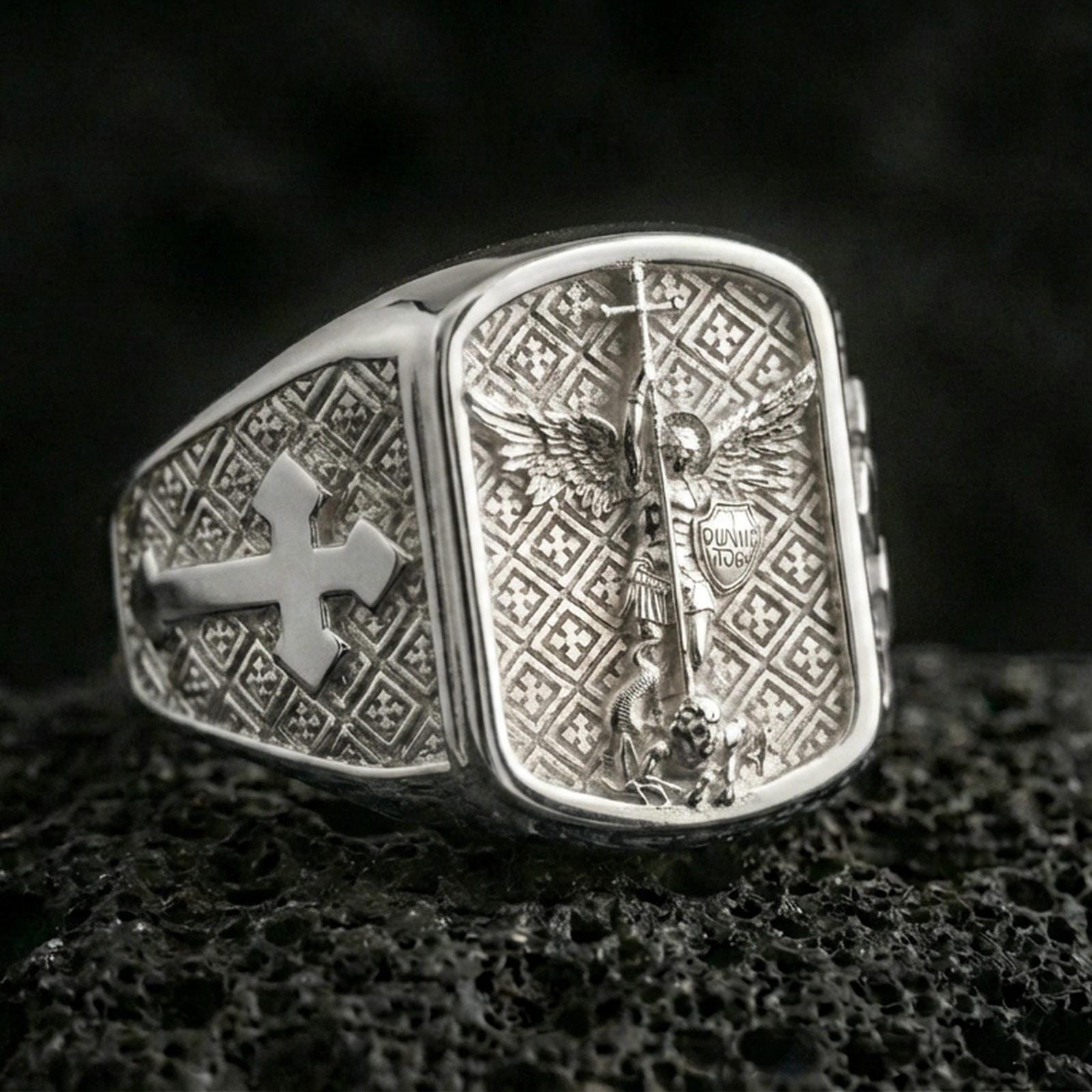 Polished silver Saint Michael signet ring on porous volcanic stone, archangel warrior engraving and cross motif sides