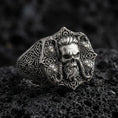 Load image into Gallery viewer, Oxidized sterling silver skull signet ring with Celtic knot engraving on black volcanic rock, macro close-up showing deep relief and antique patina
