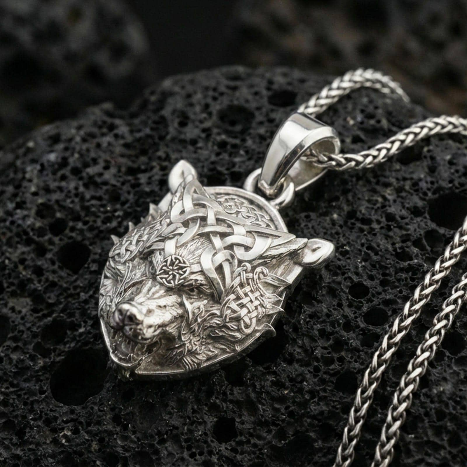 Polished silver Fenrir wolf head pendant on porous volcanic stone, Viking wolf necklace with intricate Celtic knots and Nordic symbolism