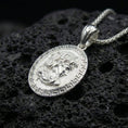 Load image into Gallery viewer, Polished silver Medusa necklace on porous volcanic stone, Greek key frame coin pendant with detailed relief portrait and vintage texture
