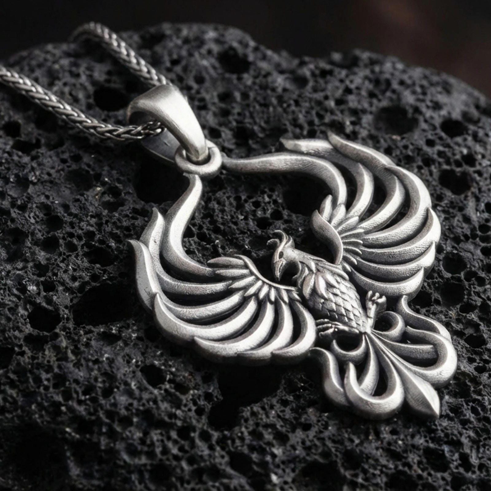 Oxidized 925 sterling silver phoenix pendant on volcanic rock, openwork wings design with sculpted feather layers