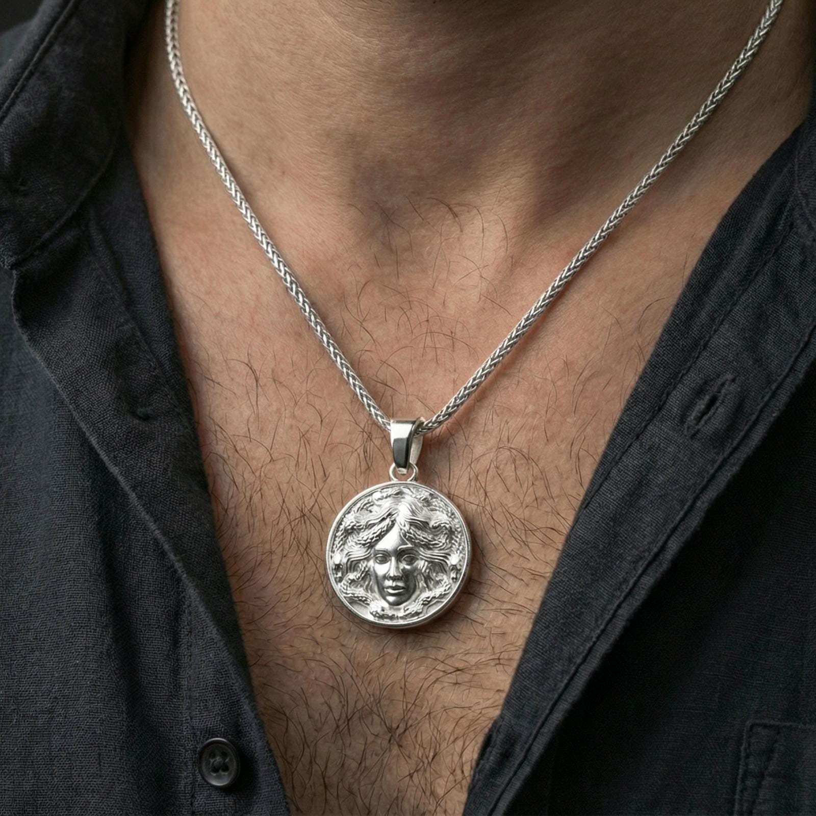 Polished silver medusa medallion necklace worn on neck, detailed coin pendant with snake hair design