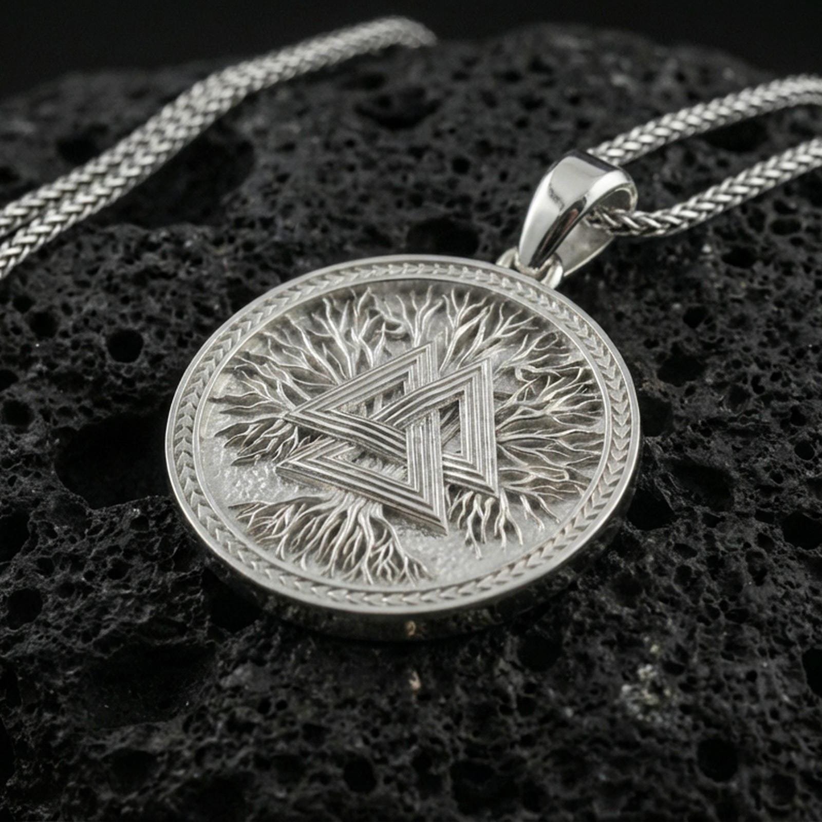 Polished silver valknut necklace on porous volcanic stone, geometric Norse knot medallion with detailed border frame