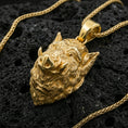 Load image into Gallery viewer, Gold plated boar head pendant on volcanic rock with braided chain, premium macro shot emphasizing raised snout, tusks, and bold metallic shine

