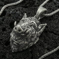 Load image into Gallery viewer, Oxidized sterling silver boar head pendant on black volcanic rock with braided chain, macro close-up showing deep fur texture and antique patina
