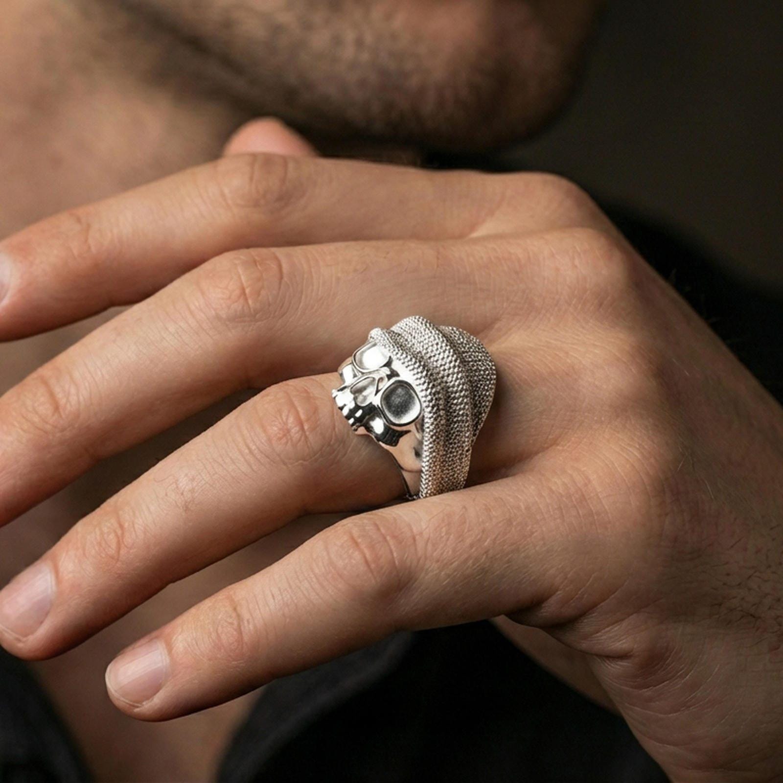 Polished silver skull ring with beanie and goggles on the finger, wearable shot highlighting the detailed knit texture and clean sculpted finish