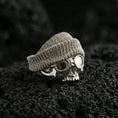 Load image into Gallery viewer, Polished silver skull ring with knit beanie and goggles on porous volcanic stone, close-up highlighting crisp skull contours and reflective lens detail
