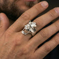 Load image into Gallery viewer, Polished silver open skull ring on the finger, wearable shot highlighting the carved grain texture and clean sculpted contours
