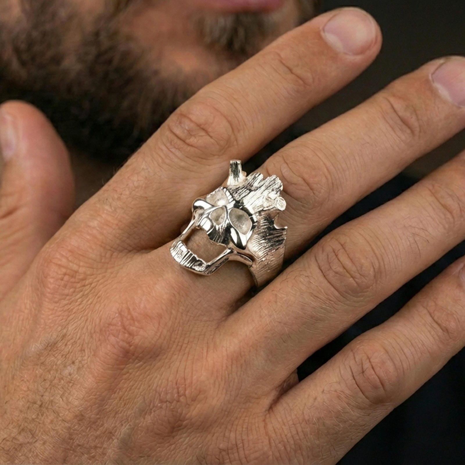 Polished silver open skull ring on the finger, wearable shot highlighting the carved grain texture and clean sculpted contours