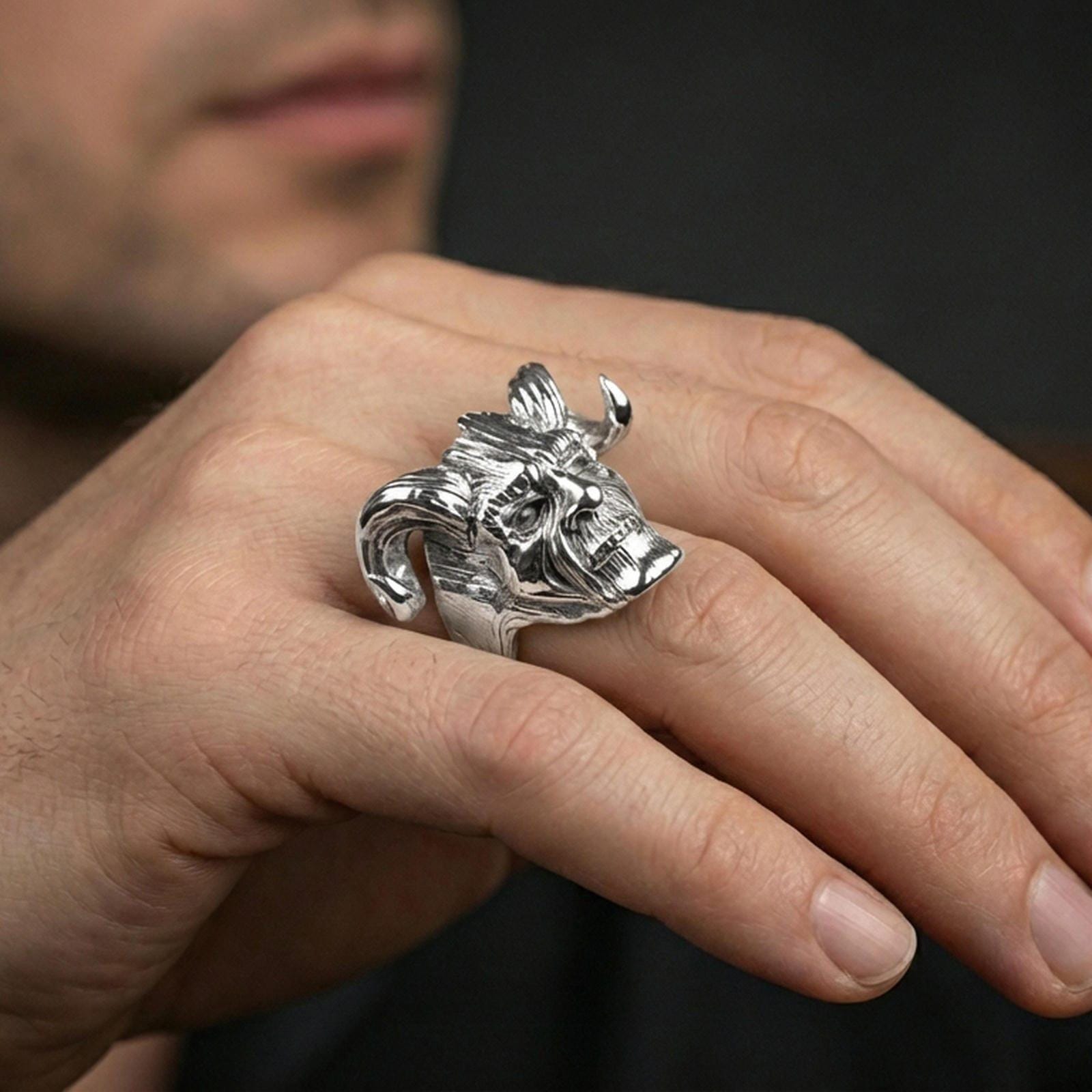 Polished silver horned skull ring on the finger, wearable shot highlighting sharp horn silhouette and detailed wood-grain carving