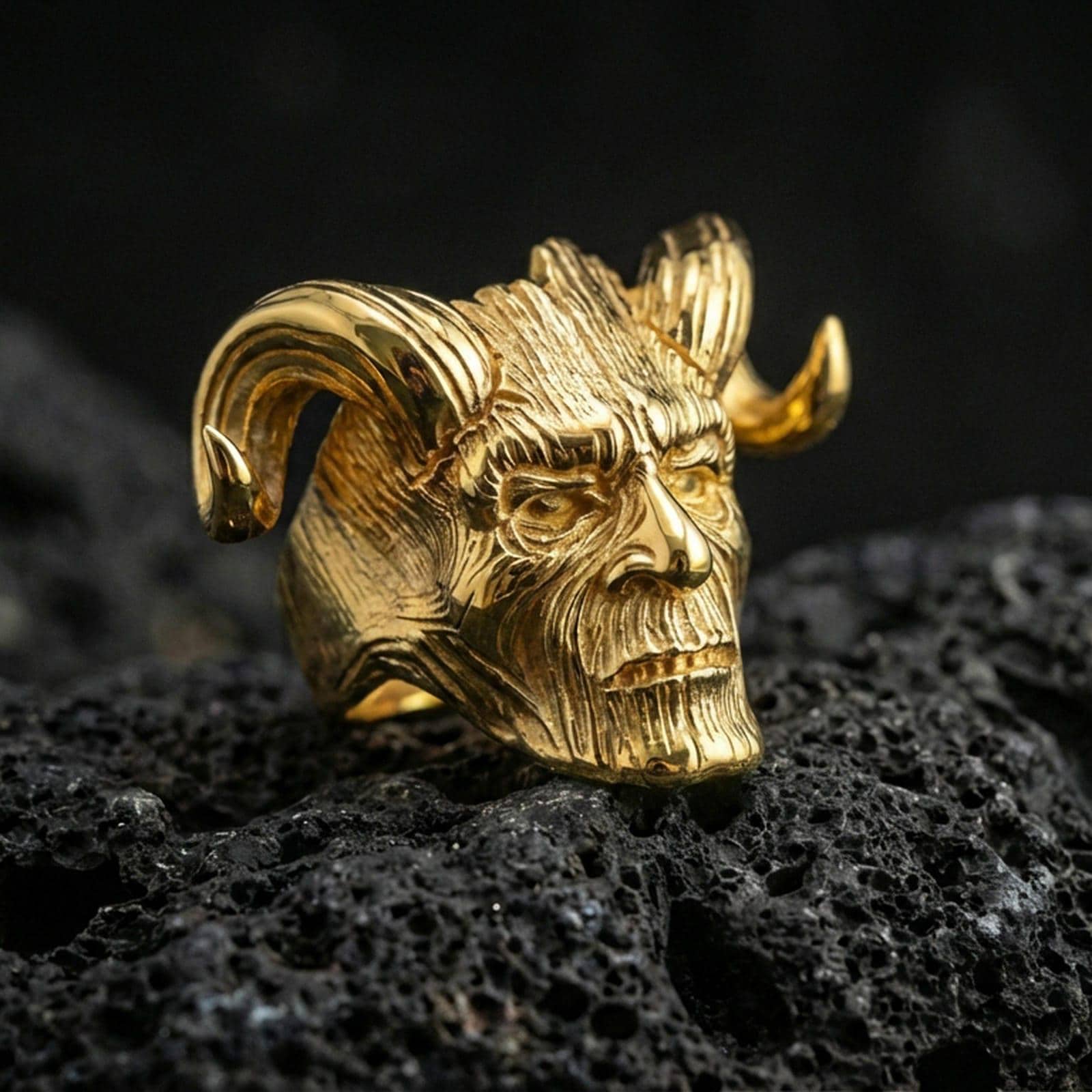 Gold plated horned skull ring with wood-textured carving on volcanic rock, premium macro photo emphasizing bold horns and high-contrast engraving