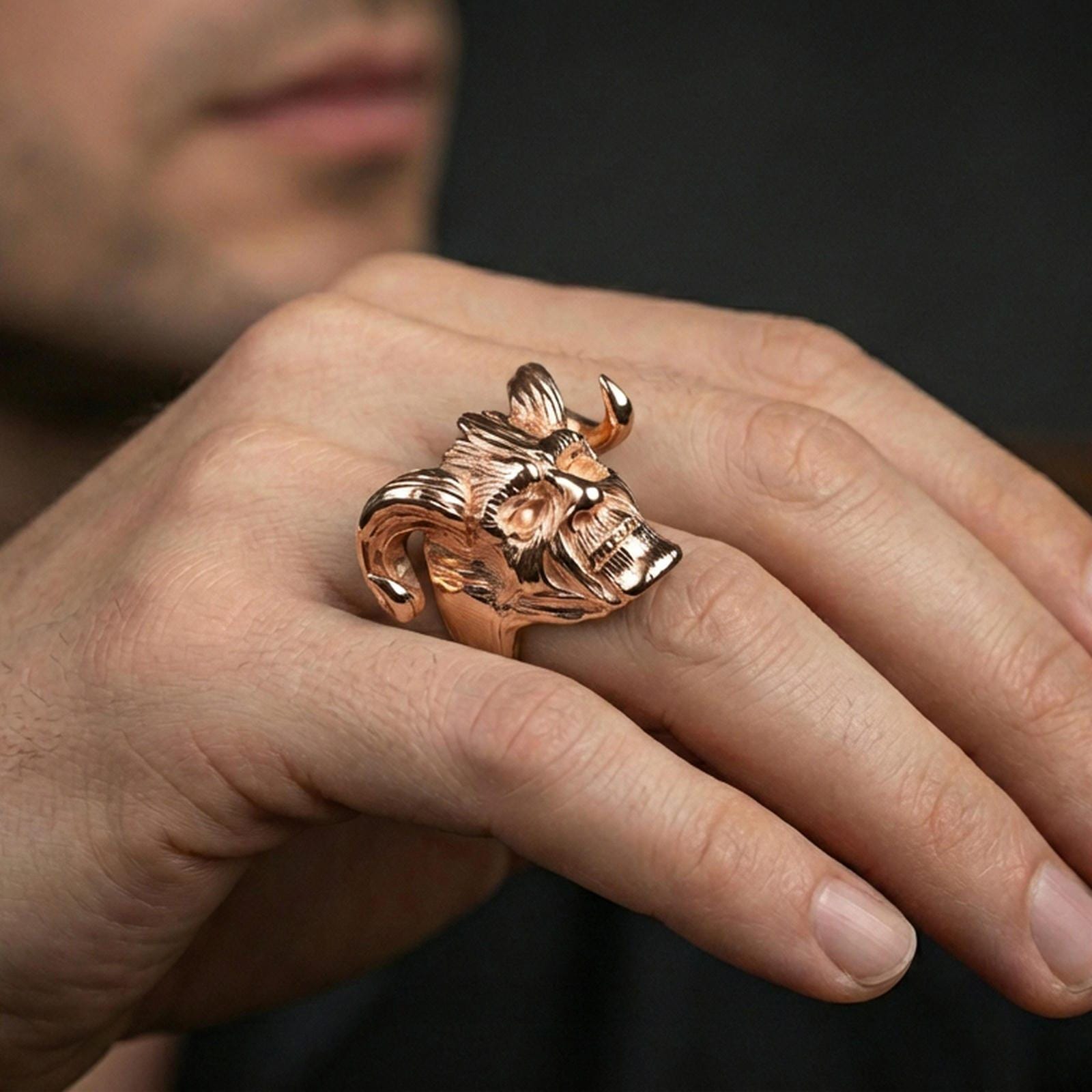 Rose gold plated horned skull ring on a finger, close-up lifestyle photo showcasing warm finish and intense sculpted facial detailing