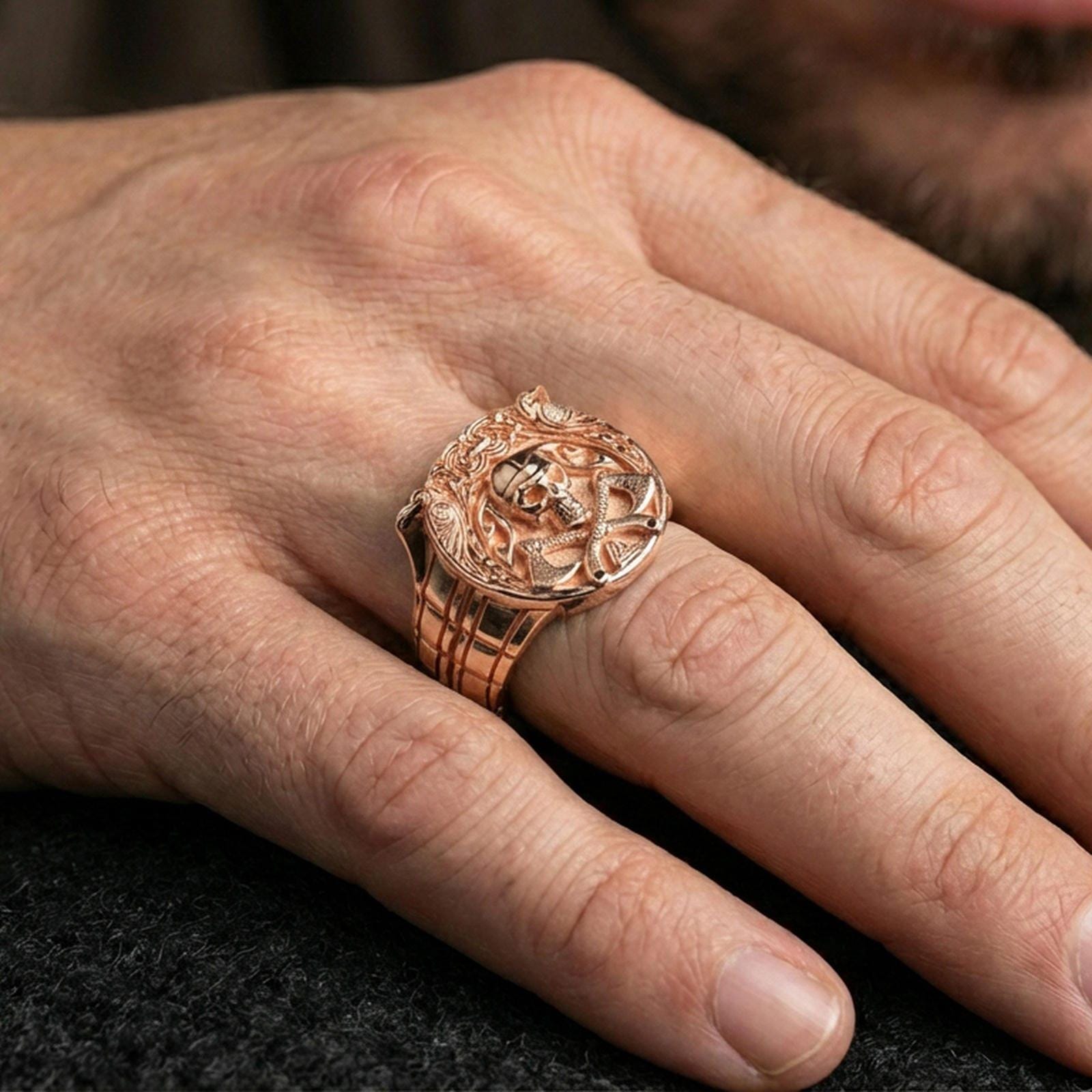 Rose gold plated Viking helmet and axes ring on a finger, close-up lifestyle photo showcasing warm finish and the detailed Norse frame engraving