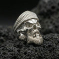 Load image into Gallery viewer, Polished silver bearded skull ring wearing a ribbed beret on porous volcanic stone, close-up highlighting crisp skull brow, beard strands and clean metal edges
