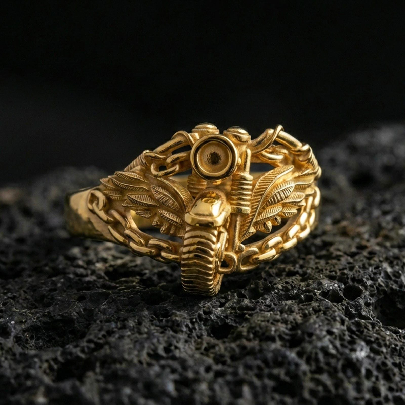 Gold plated motorcycle chain ring with winged engine motif on volcanic rock, premium macro photo emphasizing warm tone, raised mechanical texture and bold biker style