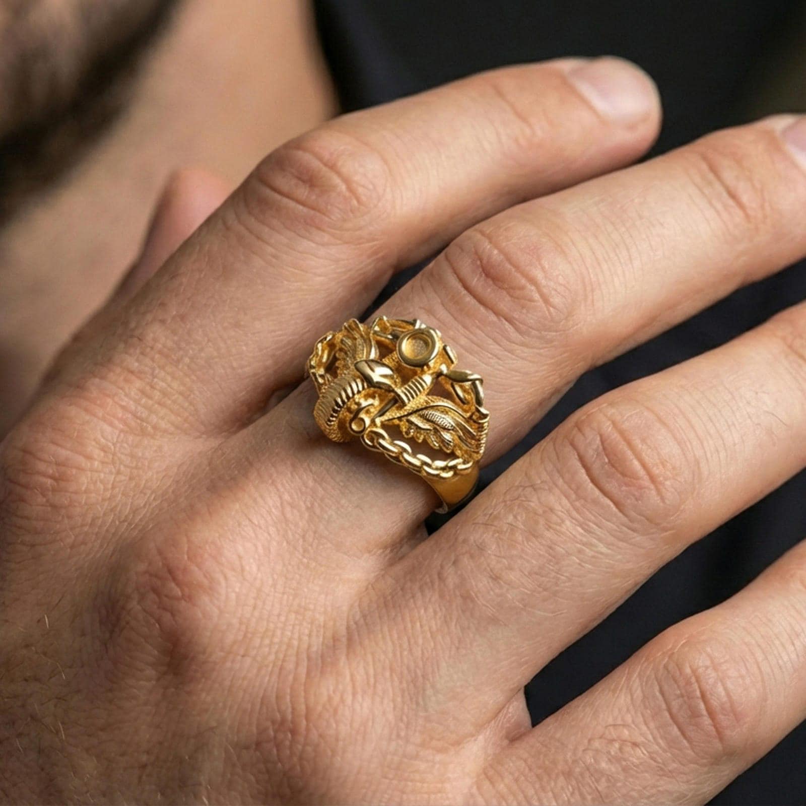 Gold plated motorcycle chain ring worn on a finger, lifestyle image emphasizing warm plating tone, winged engine motif and bold road-inspired style