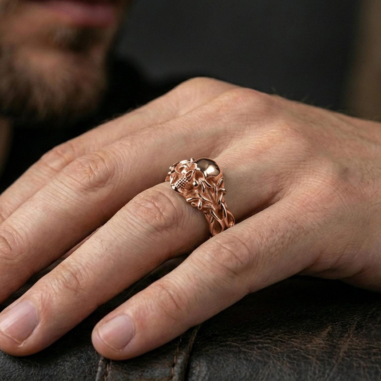Gold plated skull ring with vine wrap worn on a finger, lifestyle image emphasizing warm plating tone, intricate gothic sculpting and edgy biker style