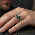 Load image into Gallery viewer, Oxidized skull and thorn vine ring worn on a finger, close-up lifestyle shot showing darkened grooves, aggressive gothic styling and bold statement look
