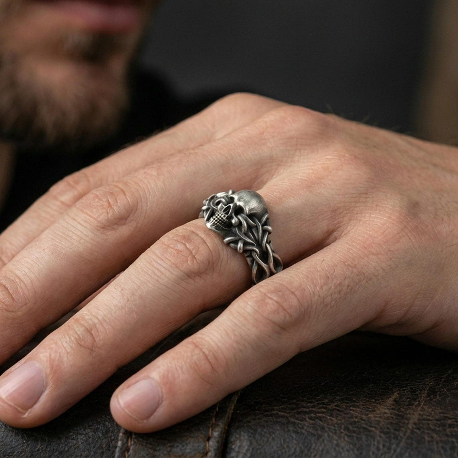 Oxidized skull and thorn vine ring worn on a finger, close-up lifestyle shot showing darkened grooves, aggressive gothic styling and bold statement look