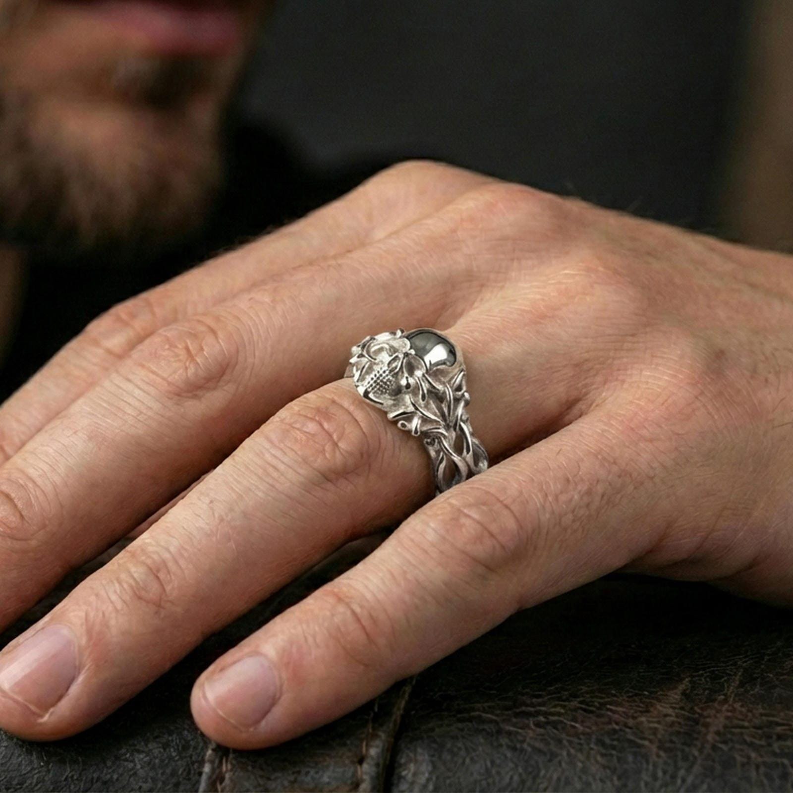 Polished silver skull vine ring worn on the finger, wearable photo highlighting reflective finish, crisp skull teeth detail and braided vine band