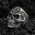 Load image into Gallery viewer, Oxidized sterling silver skull ring with Masonic square and compass “G” emblem on the crown, on black volcanic rock in a dark macro studio shot

