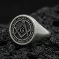 Load image into Gallery viewer, Oxidized sterling silver Masonic signet ring with square and compass “G” emblem and Latin motto, macro photo on black volcanic rock
