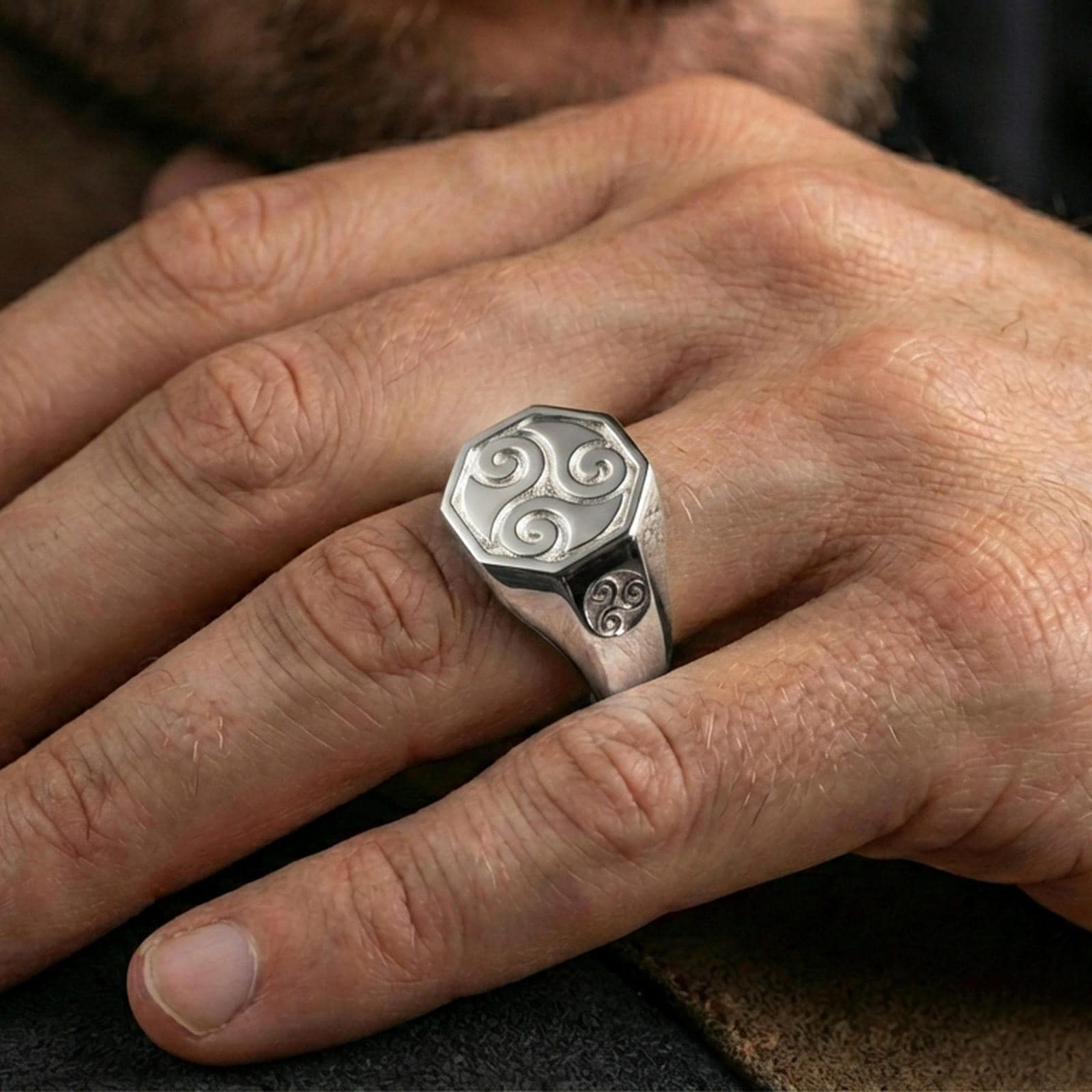 Polished silver triskelion signet ring on the finger, wearable shot emphasizing the octagonal face and clean geometric band
