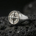 Load image into Gallery viewer, Polished silver compass signet ring featuring a 3D wind rose star and beaded border edge, close-up product shot on volcanic stone

