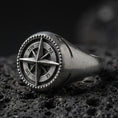 Load image into Gallery viewer, Oxidized sterling silver compass signet ring with raised wind-rose star and NW NE SW SE lettering, macro photo on black volcanic rock
