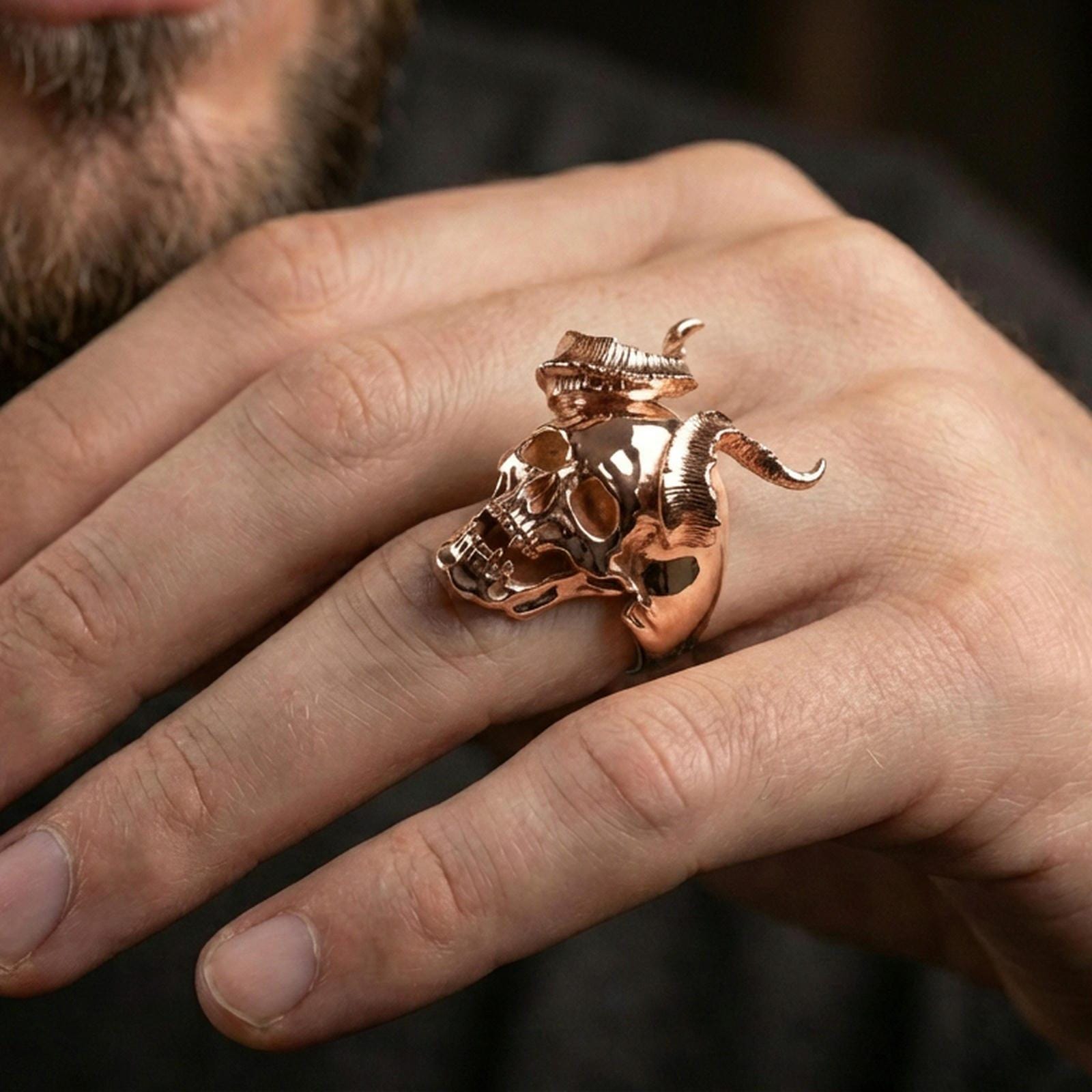 Rose gold plated demon skull ring on a finger, close-up lifestyle photo showcasing the horned skull silhouette and bold gothic look